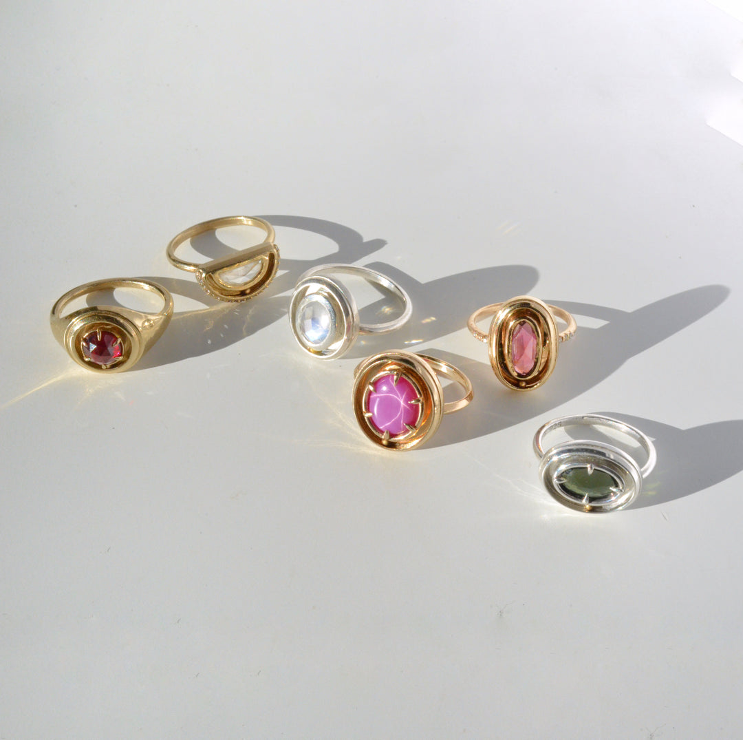 Set of gold and silver kinetic orbit rings with gemstones on a white surface. Handcrafted by Emma Brooke Jewelry.