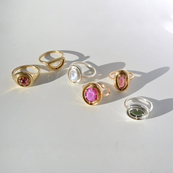 Set of gold and silver kinetic orbit rings with gemstones on a white surface. Handcrafted by Emma Brooke Jewelry.