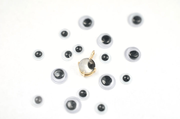 Googly eye charm in gold surrounded by googly eyes