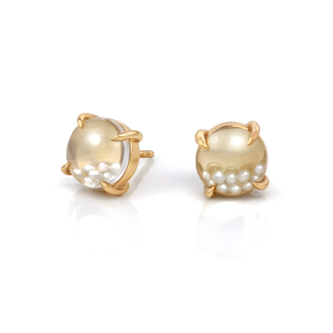 Gold kinetic shaker earrings with loose pearls behind glass domes on a white background