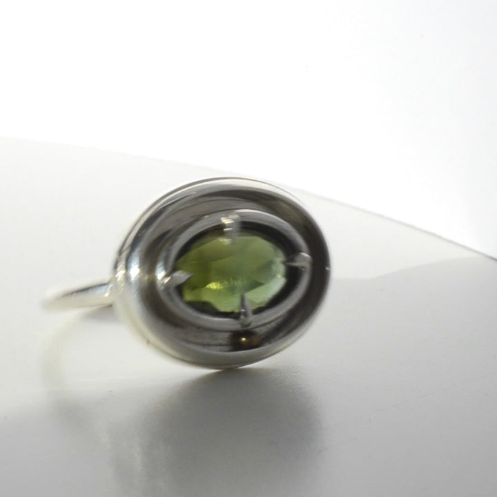 A kinetic silver ring with a green gemstone, featuring a moving rolling gold ball. Ring for anxiety or fidgeting.