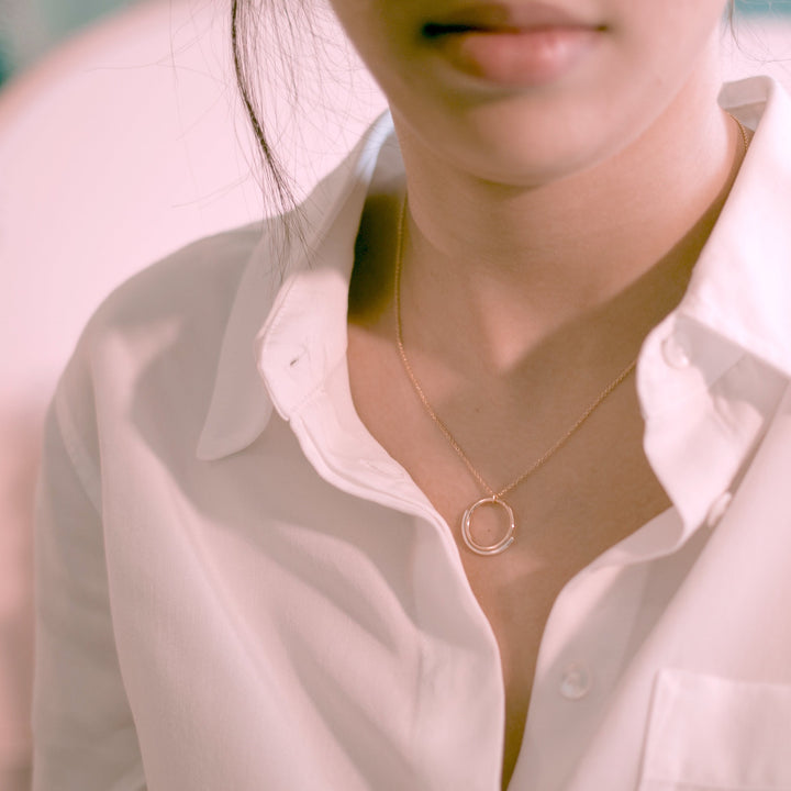 Emma Brooke Jewelry Sun and Moon necklace modeled. Model wears a white button up shirt with the minimal circle gold and silver minimal necklace.