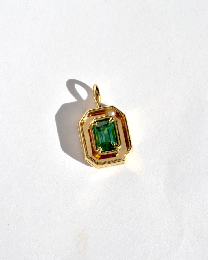a gold pendant with an emerald cut green tourmaline and a movable white pearl