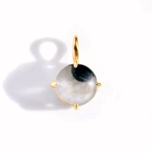 a GIF of a googly eye necklace charm, in yellow gold, showing the googly eye looking around.