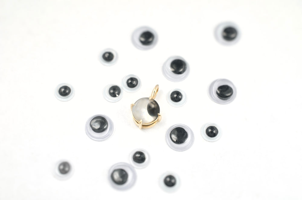 Googly eye charm in gold surrounded by googly eyes
