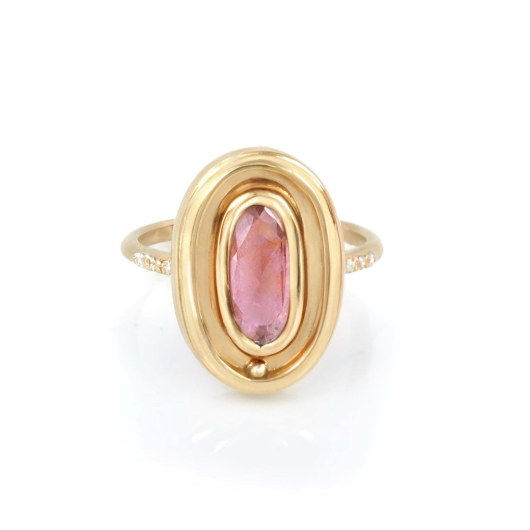 A solid gold kinetic anxiety ring with a pink gemstone on a white background.