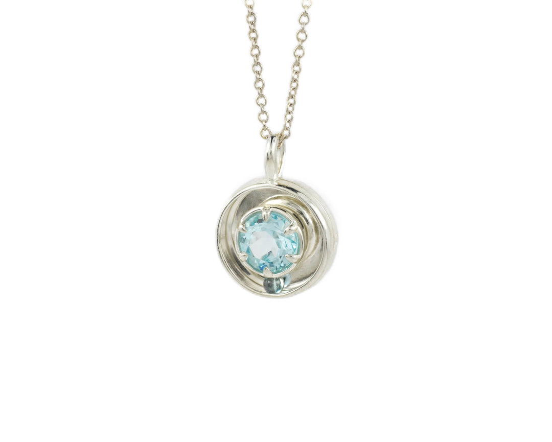 silver pendant with blue gemstones and a rolling blue marble