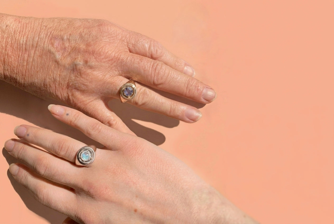an older and younger women's hands, wearing matching orbit rings, one in silver and one in gold
