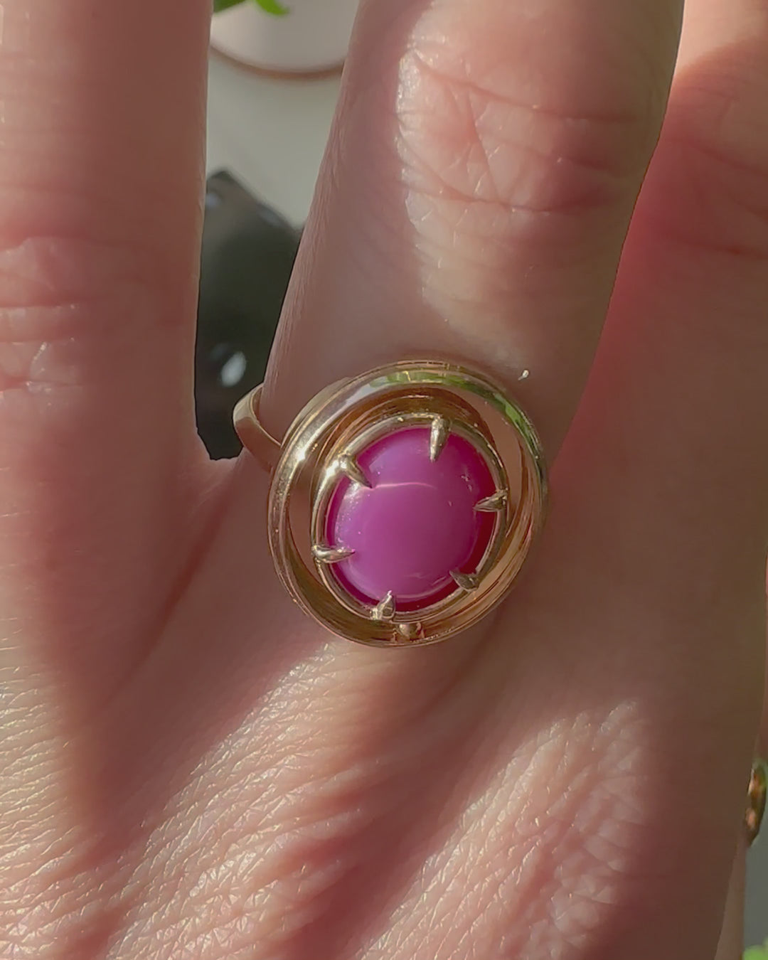 The kinetic ruby orbit ring by Emma Brooke shown in motion. A model wears the ring on their finger, moving their hand to show the kinetic elements of the ring, and show the star effect of the star ruby moving in the sun.