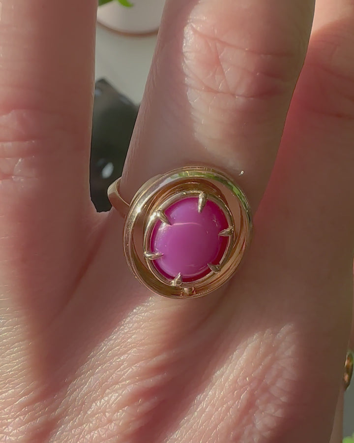 The kinetic ruby orbit ring by Emma Brooke shown in motion. A model wears the ring on their finger, moving their hand to show the kinetic elements of the ring, and show the star effect of the star ruby moving in the sun.