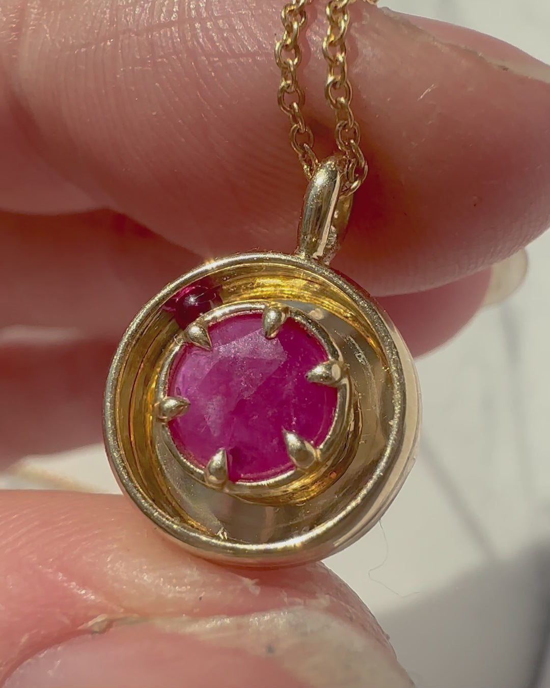 a gold and ruby necklace, with a moving ruby ball that moves in circles inside the pendant.