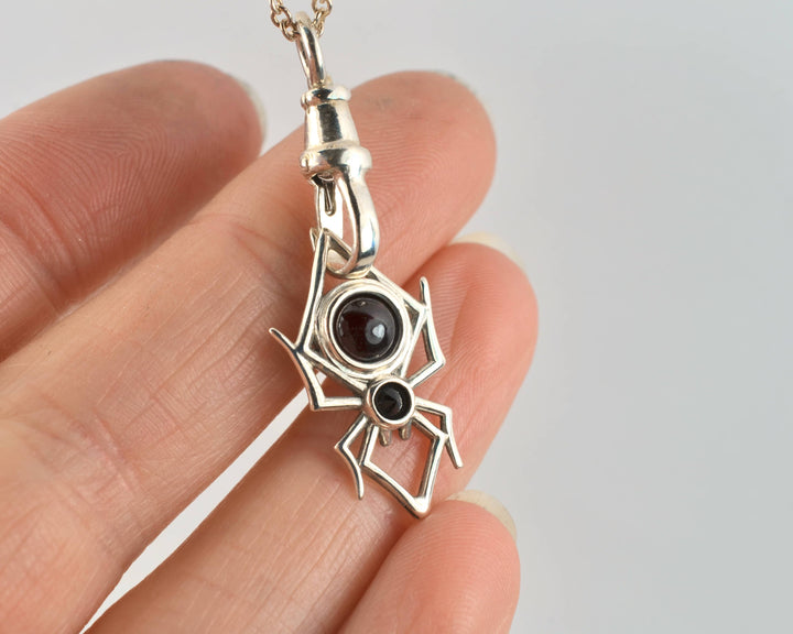 a spider shaped pendant in sterling silver with two black gemstones,  styled on a vintage dog-clasp style necklace.